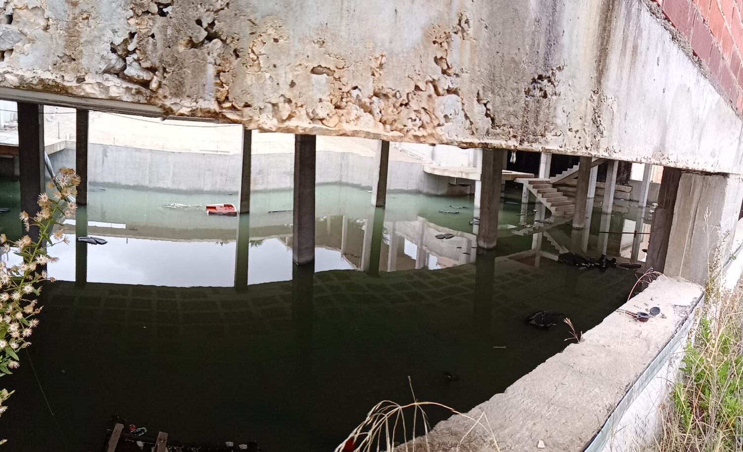 &quot;Piscina&quot; de agua, con basura y otros restos, que se ha formado en las obras de construcción del futuro auditorio municipal.