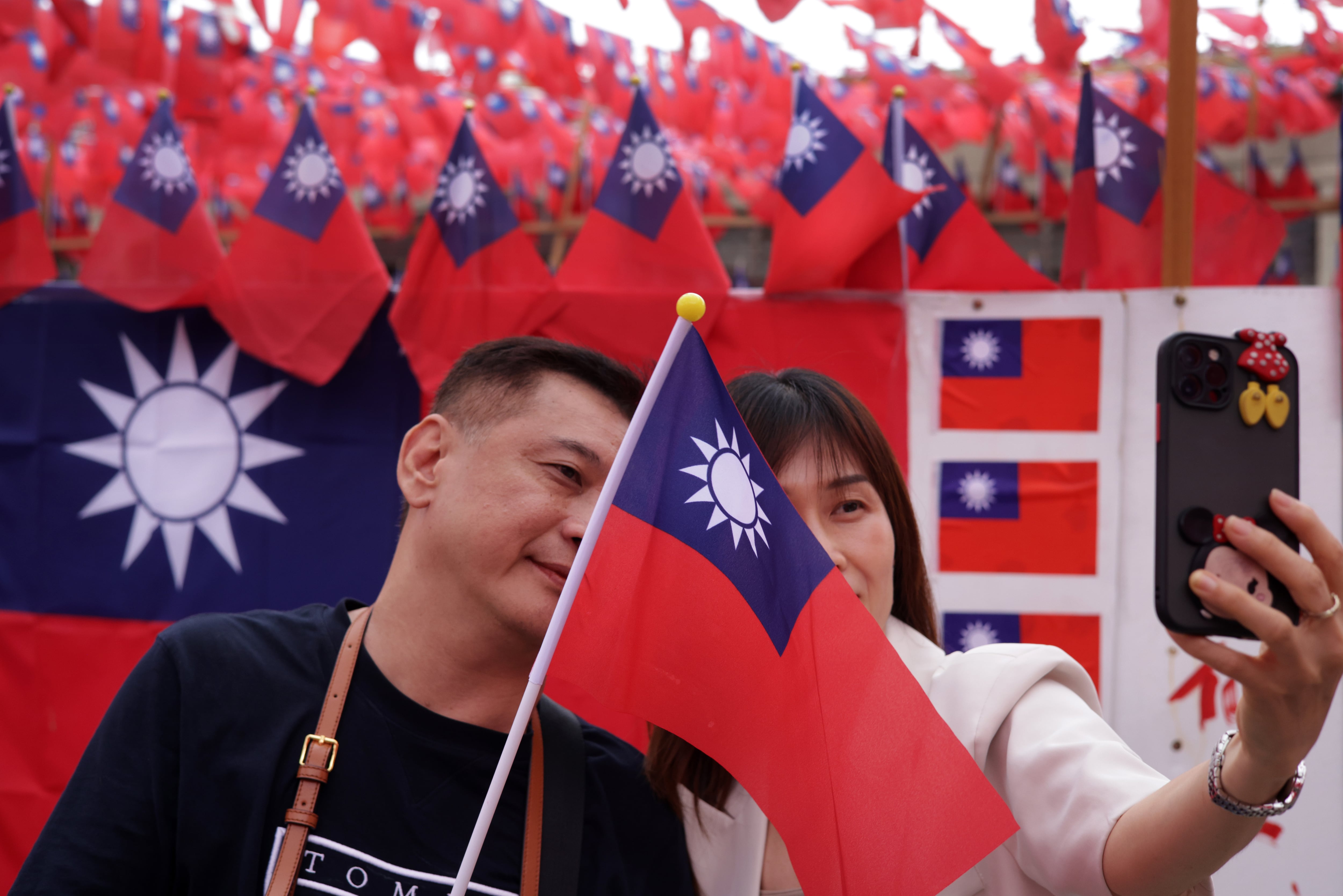 Una pareja se hace fotos ante banderas de Taiwán en Taipei