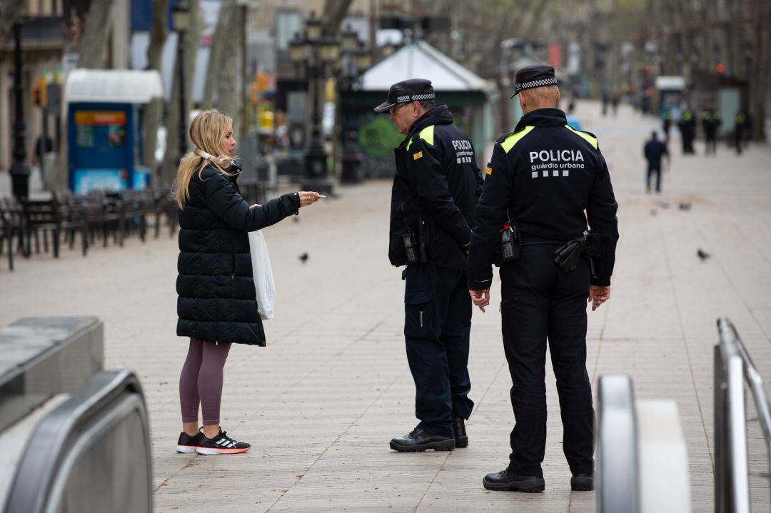 Dos agentes de la Policía hablan con una mujer en una calle de Barcelona