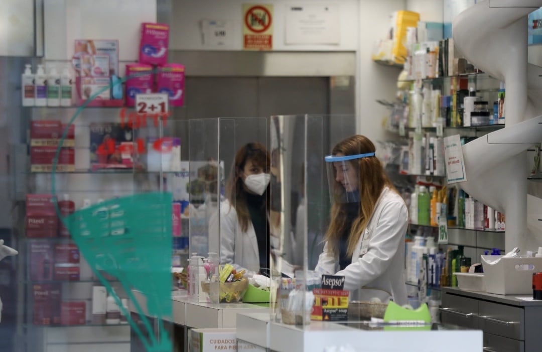 Dos farmacéuticas trabajan protegidas con mascarillas y pantallas protectoras