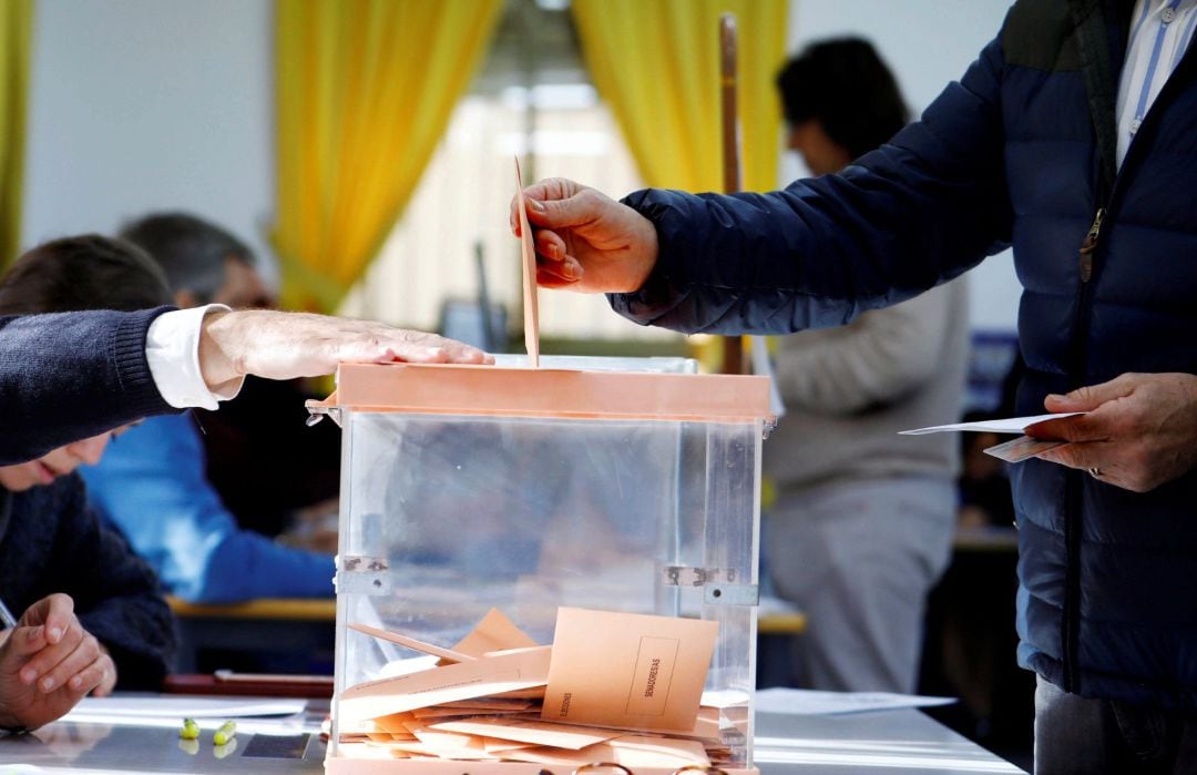 Un hombre introduce su papeleta en una urna de un colegio electoral