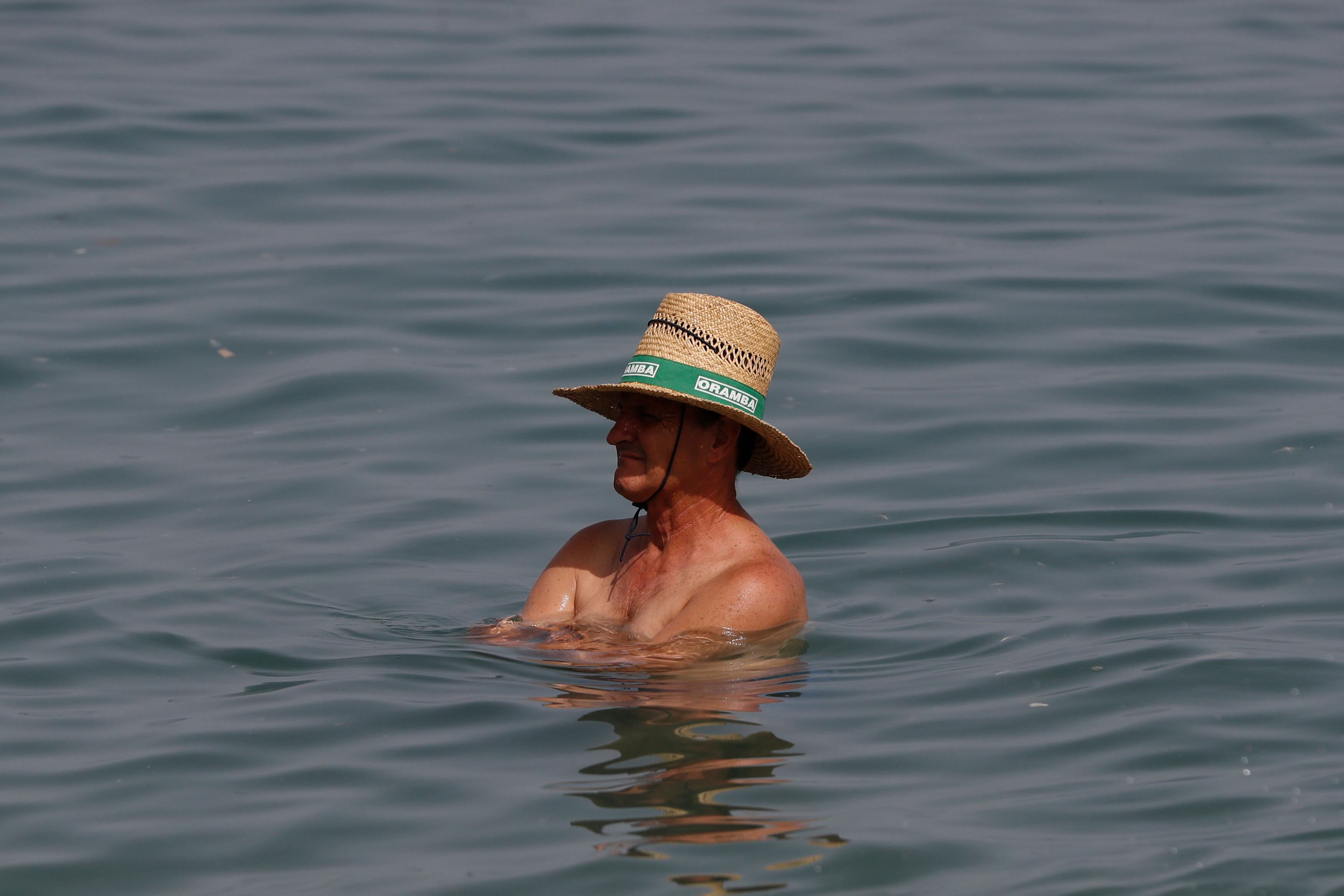GRAFAND3671. MÁLAGA, 10/07/2023.- Un hombre con sombrero dentro del agua de la playa de la Malagueta en Málaga, este lunes cuando la segunda ola de calor de este verano dejará en el día de hoy y mañana martes temperaturas extremas incluso hasta los 45 grados en puntos de Andalucía y en la mayor parte del país valores que oscilarán entre los 38-43 grados en amplias zonas de la geografía española. EFE/Jorge Zapata
