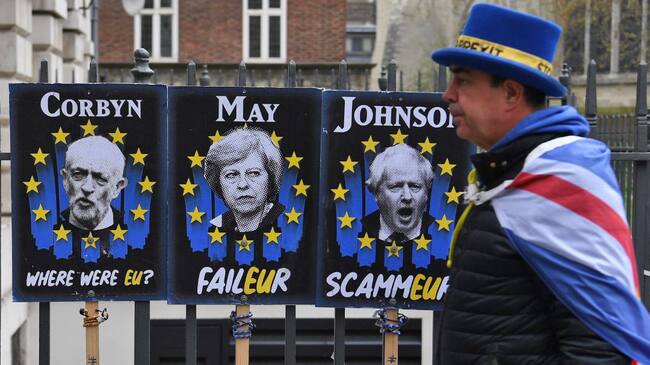 Un manifestante a favor de la estancia del Reino Unido en la Unión Europea camina junto a carteles que critican a Jeremy Corbyn