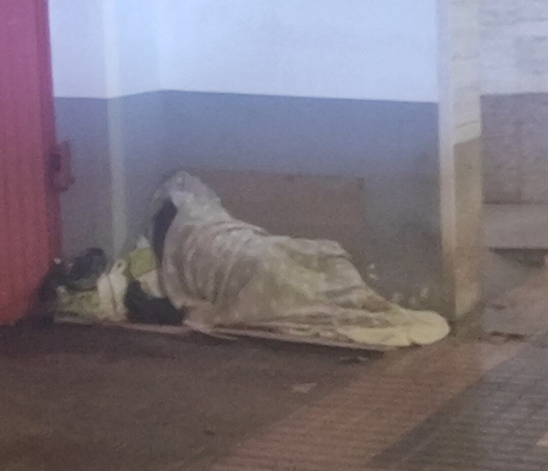 Una persona sin hogar durmiendo en la puerta de un garaje en la calle Juan Muñoz Delgado en Cartagena hace unos días