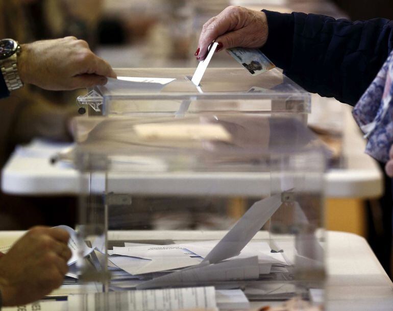 Una mujer introduce su voto en una urna 