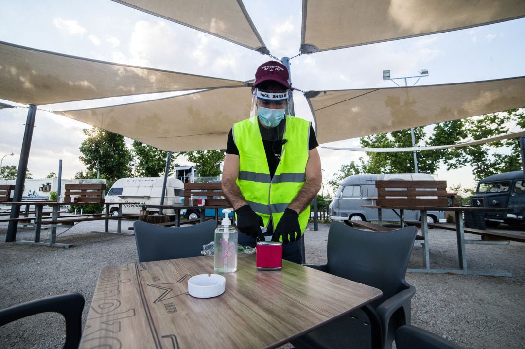 Un empleado desinfecta una mesa en la zona de bar durante la apertura del Auto-Cine RACE con las medidas de seguridad dictadas por el Gobierno de España durante la pandemia Covid-19.