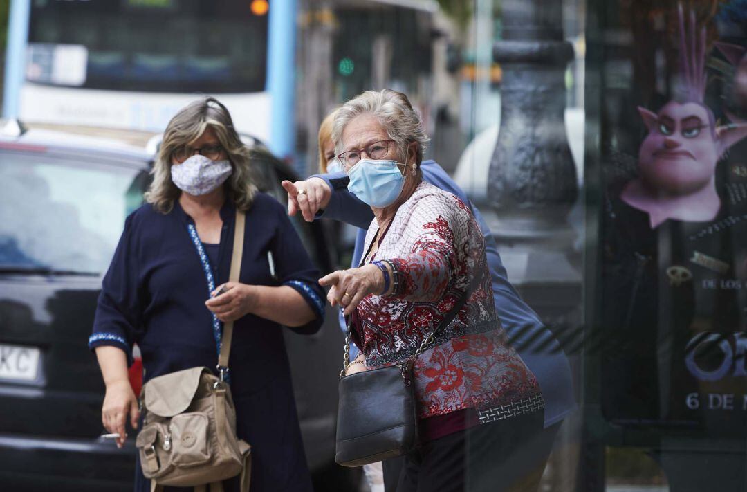 Transeúntes pasean por calles de Santander con mascarilla.