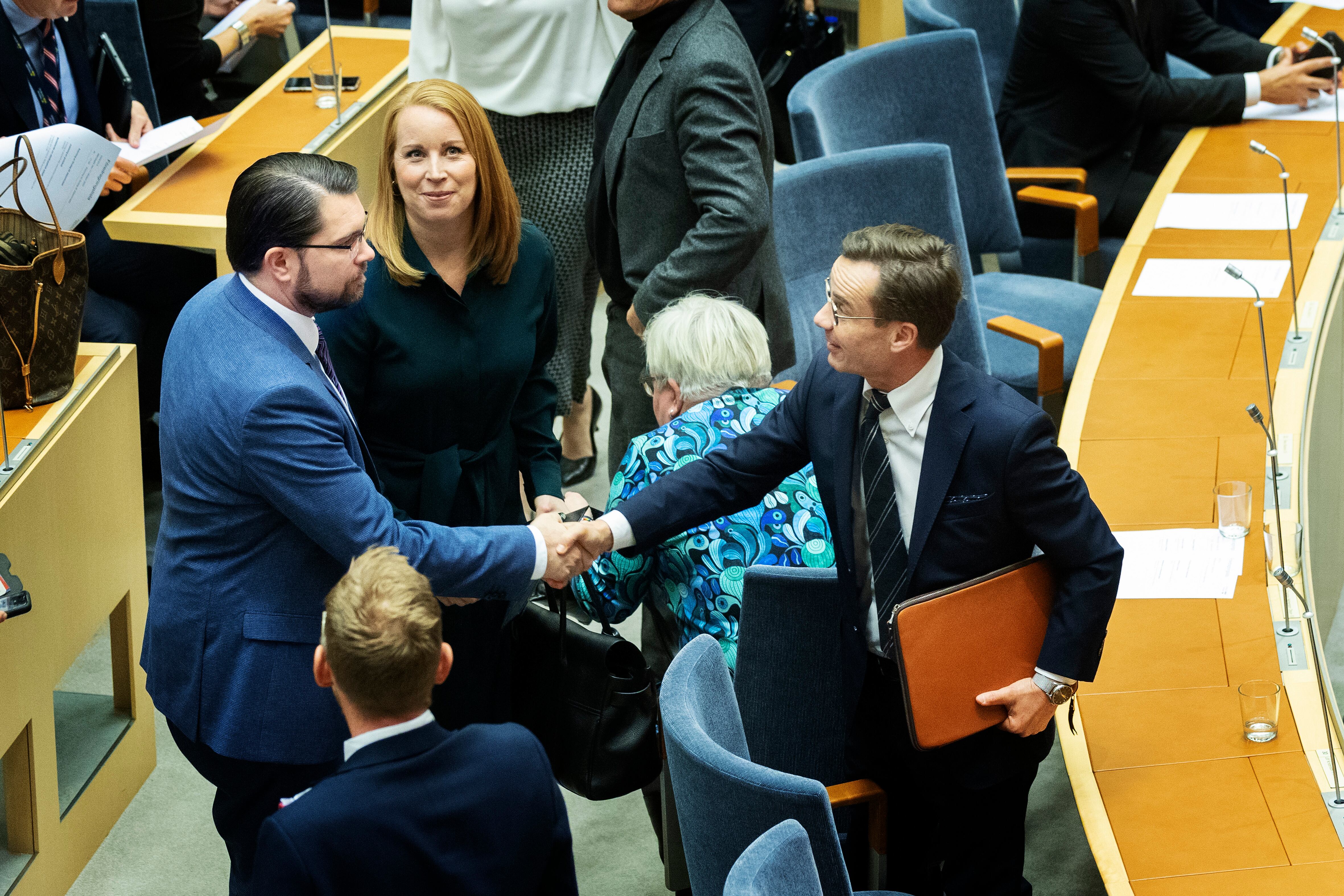 El líder del partido ultraderechista Demócratas de Suecia, Jimmie Akesson (izquierda) saluda al primer ministro Ulf Kristersson en el parlamento nacional
