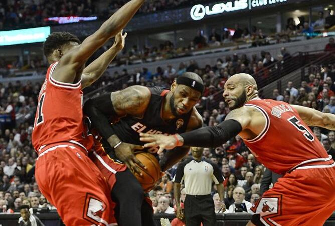 Los jugadores de los Bulls Jimmy Butler (i) y Carlos Boozer (d) ante LeBron James (c) de los Heat