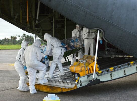 Personal médico subiendo al enfermo de ébola Manuel García al avión hercules en el aeropuerto de Freetown