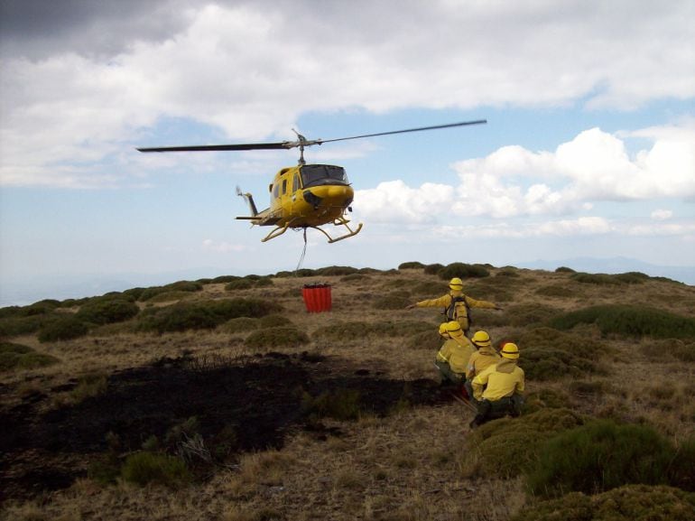 Bomberos forestales junto a un helicóptero.