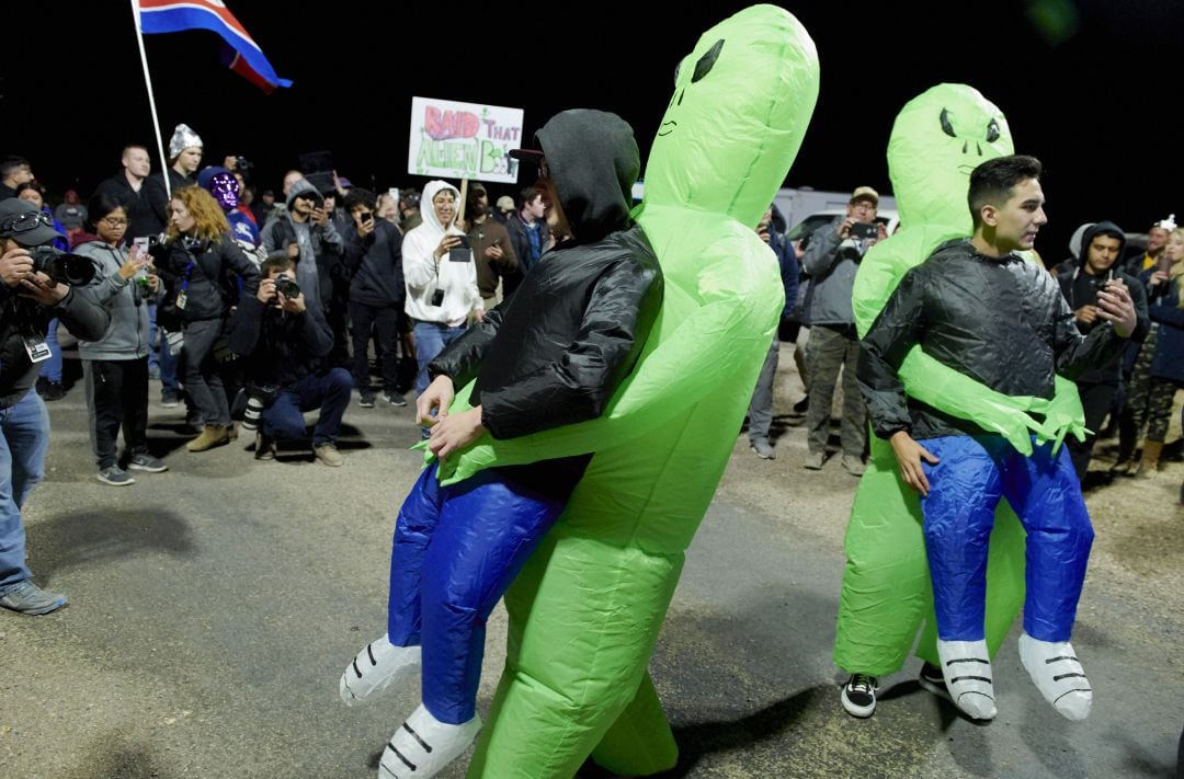 Decenas de personas se reúnen de madrugada frente a una base aérea militar de los Estados Unidos. 