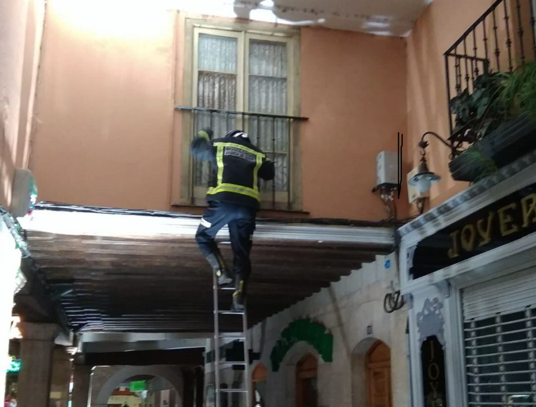 Uno de los bombeross accede a la ventada de la vivienda afectada.