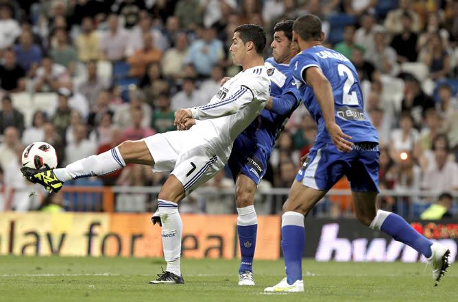 El delantero portugués del Real Madrid, Cristiano Ronaldo, intenta rematar entre los defensas Miguel Torres  y Cata Díaz durante del encuentro del Santiago Bernabéu contra el Getafe.