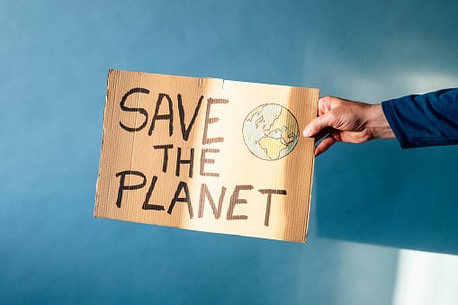 Man&#039;s hand holding a cardboard sign that says SAVE THE PLANET