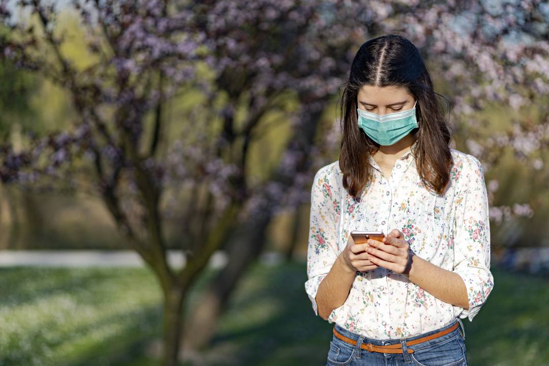 Una joven pasea con un teléfono móvil en la mano.
