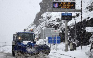 Un rètol a Esterri d'Àneu que indica l'ús obligatori de cadenes per circular pel Port de la Bonaigua i una màquina llevaneu netejant les carretere