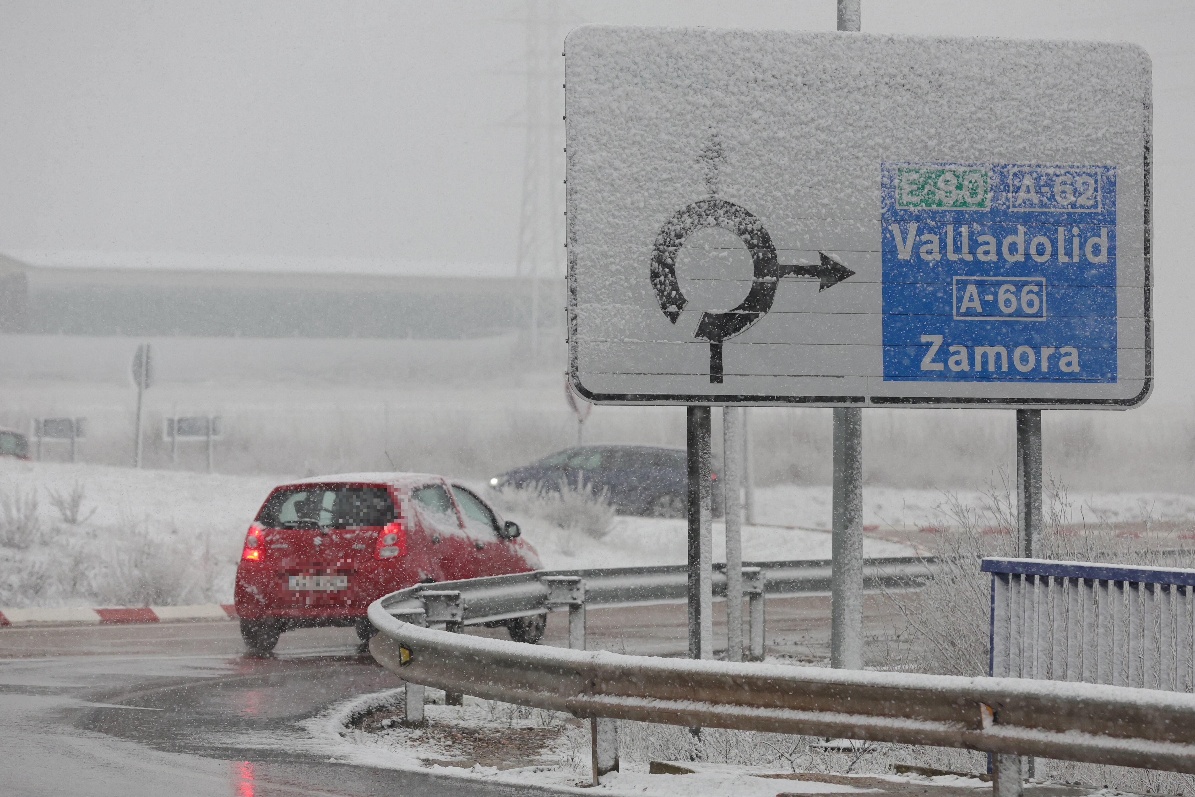 Vehículos circulan por la carretera mientras caen los primeros copos de una nevada