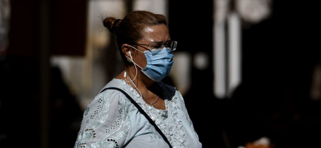 Mujer caminando por la calle con mascarilla.