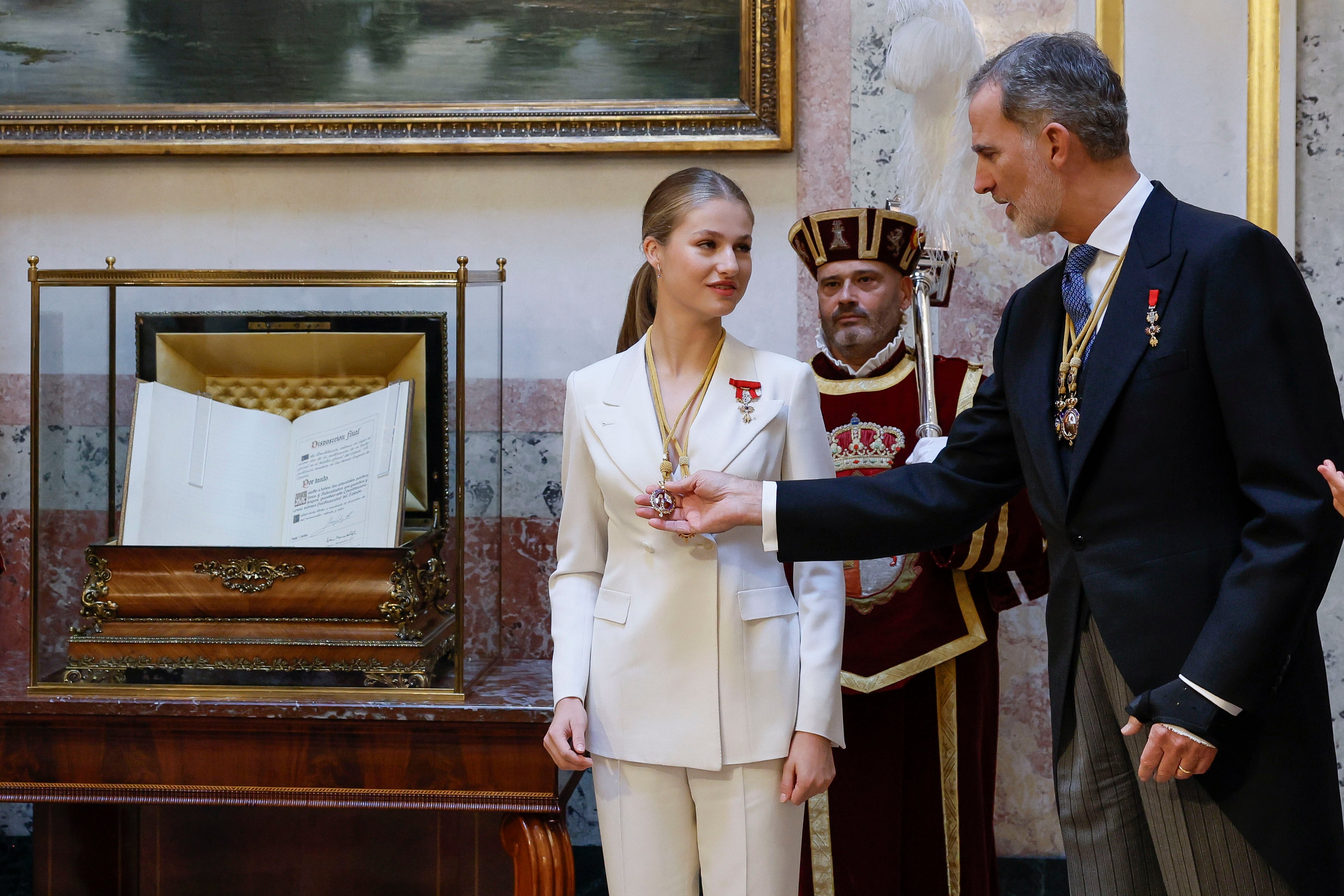 El rey Felipe VI ayuda a su hija, la princesa Leonor (c), tras serle impuestas a la heredera al trono las Medallas del Congreso y Senado en el escritorio del Congreso.