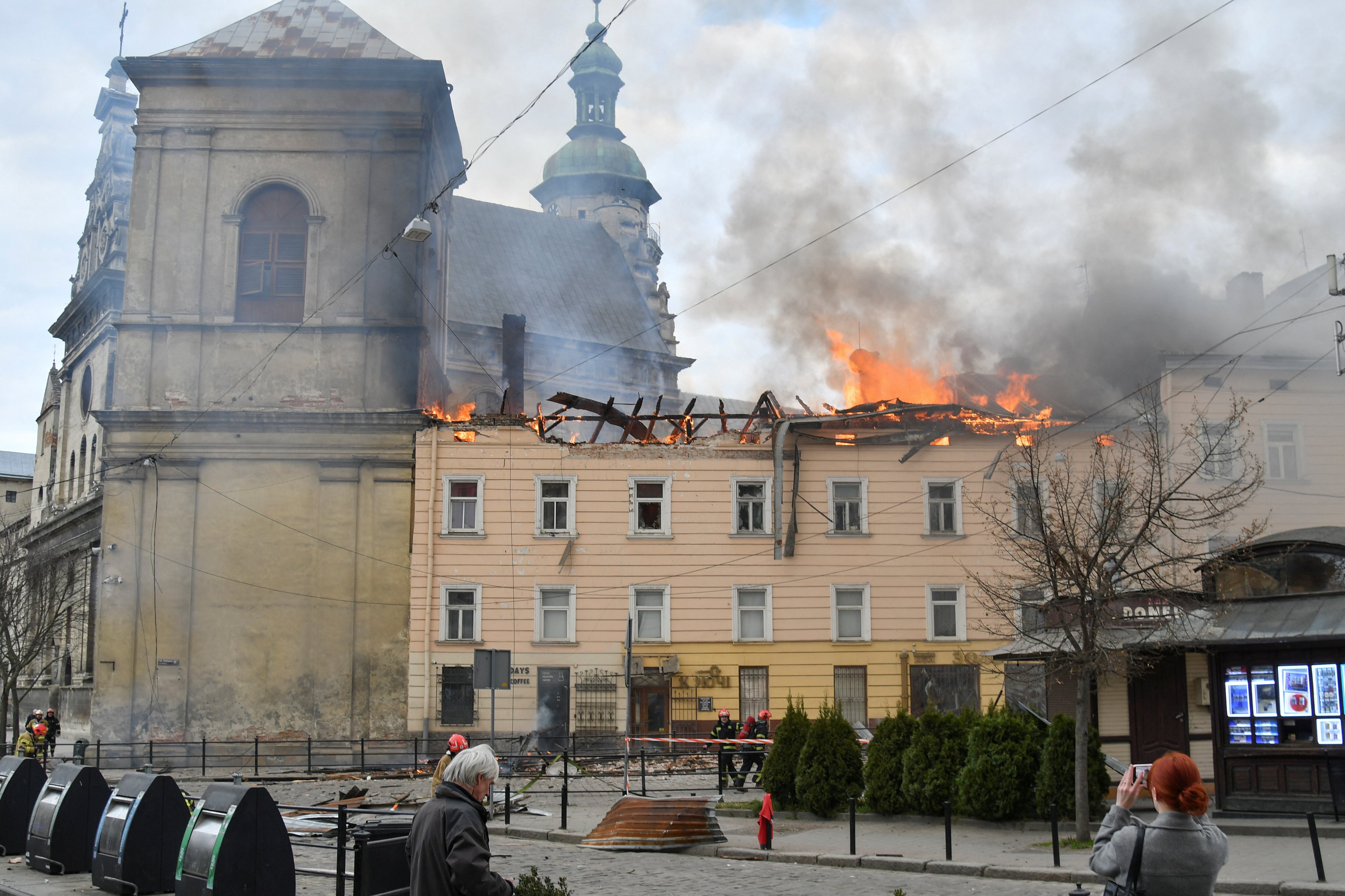 Los vecinos observan a los bomberos que trabajan en el lugar donde un edificio ha sido alcanzado por un ataque con drones rusos, en el marco de la invasión de Ucrania por parte de Rusia, en el centro de Leópolis (Ucrania), el 24 de marzo de 2026.