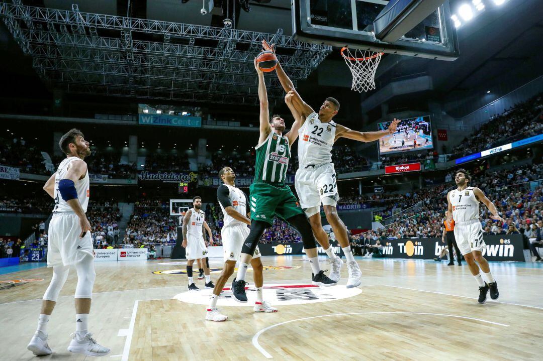 El jugador del Real Madrid Tavares (segundo dcha.) tapona el lanzamiento de Papagiannis del Panathinaikos  (centro), durante el segundo partido de los cuartos de final de la Euroliga disputado en el Wizink Center, en Madrid