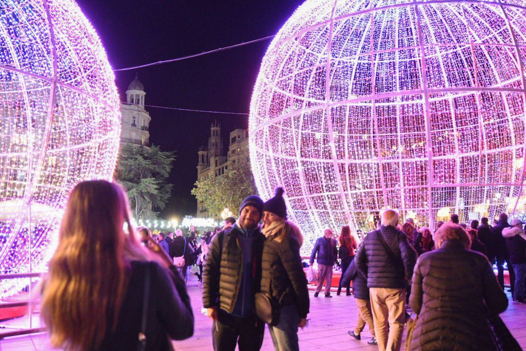 Dos personas se hacen una foto en la iluminación navideña de la plaza del Ayuntamiento de València