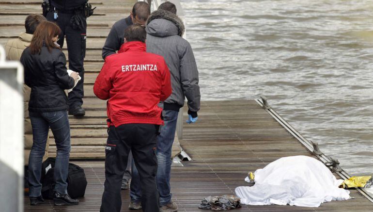 GRA152. BILBAO, 19/01/2015.- Agentes de la Ertzaintza junto al cuerpo sin vida de una persona, aparentemente un hombre de unos cincuenta años, que ha aparecido esta mañana flotando en aguas de la ría de Bilbao, a la altura del puente Zubi Zuri de la capital vizcaína. EFE/Alfredo Aldai