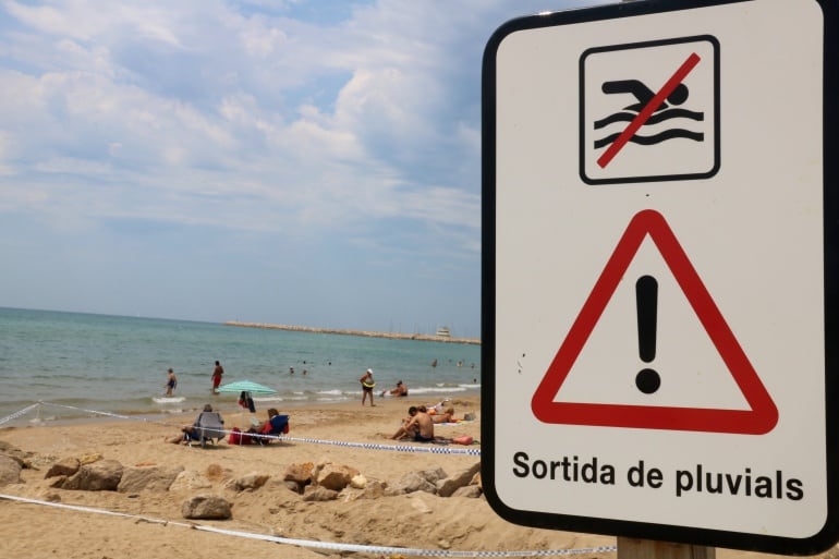 Cartell que indica la sortida d'aigües pluvials, amb una cinta policial que en delimita el perímetre per un vessament fecal.