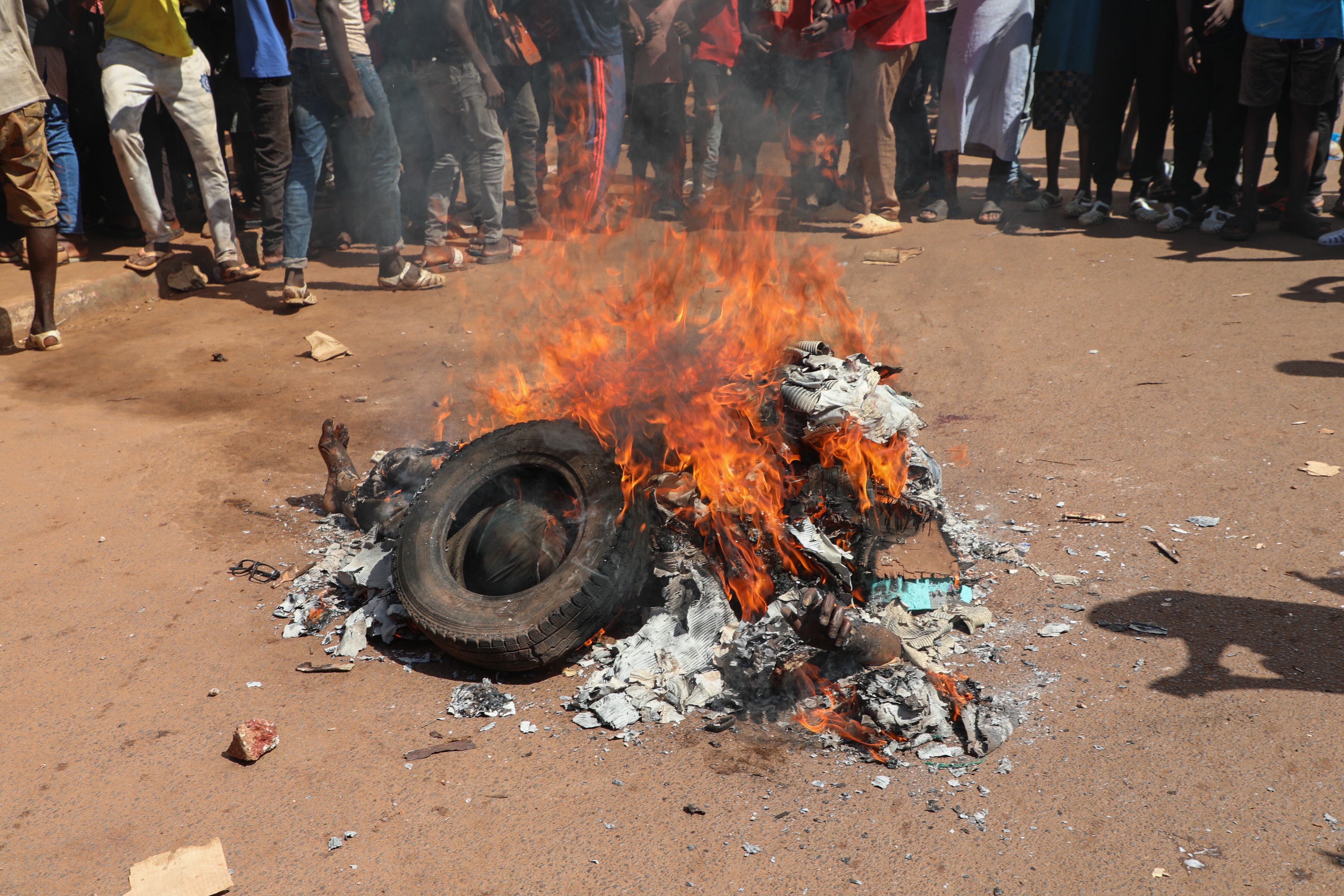 Residentes locales observan el cuerpo de un hombre quemado vivo tras ser sospechoso de ser un atacante en Bamako