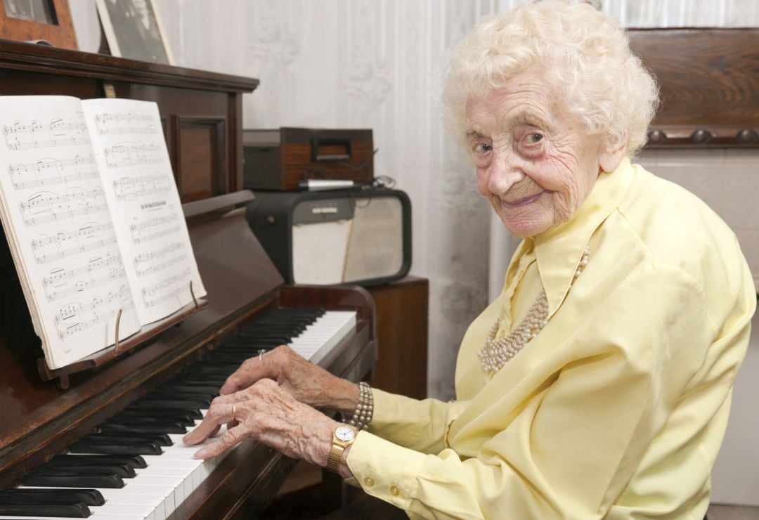 Una mujer de edad avanzada toca el piano. 