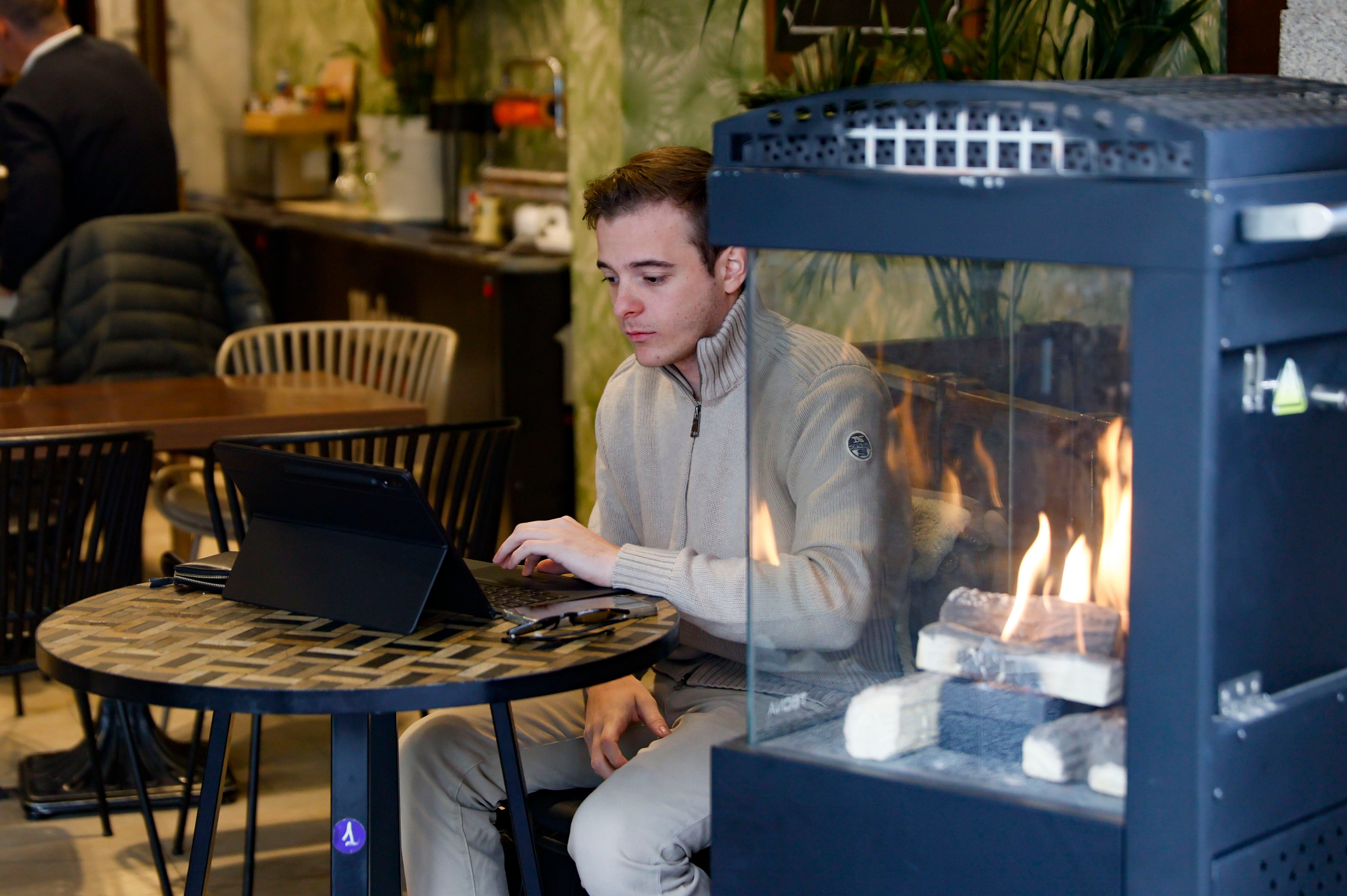 Un hombre utiliza un ordenador al lado de una chimenea en una cafetería este martes en Madrid.