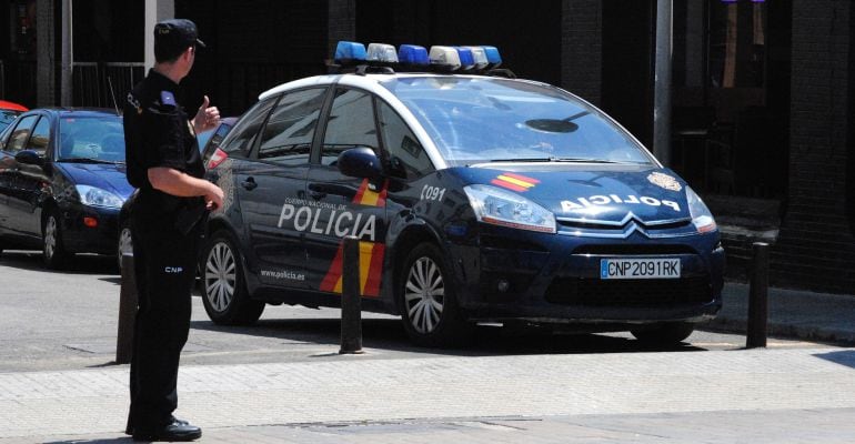 Un agente de la Policía Nacional frente a un coche patrulla