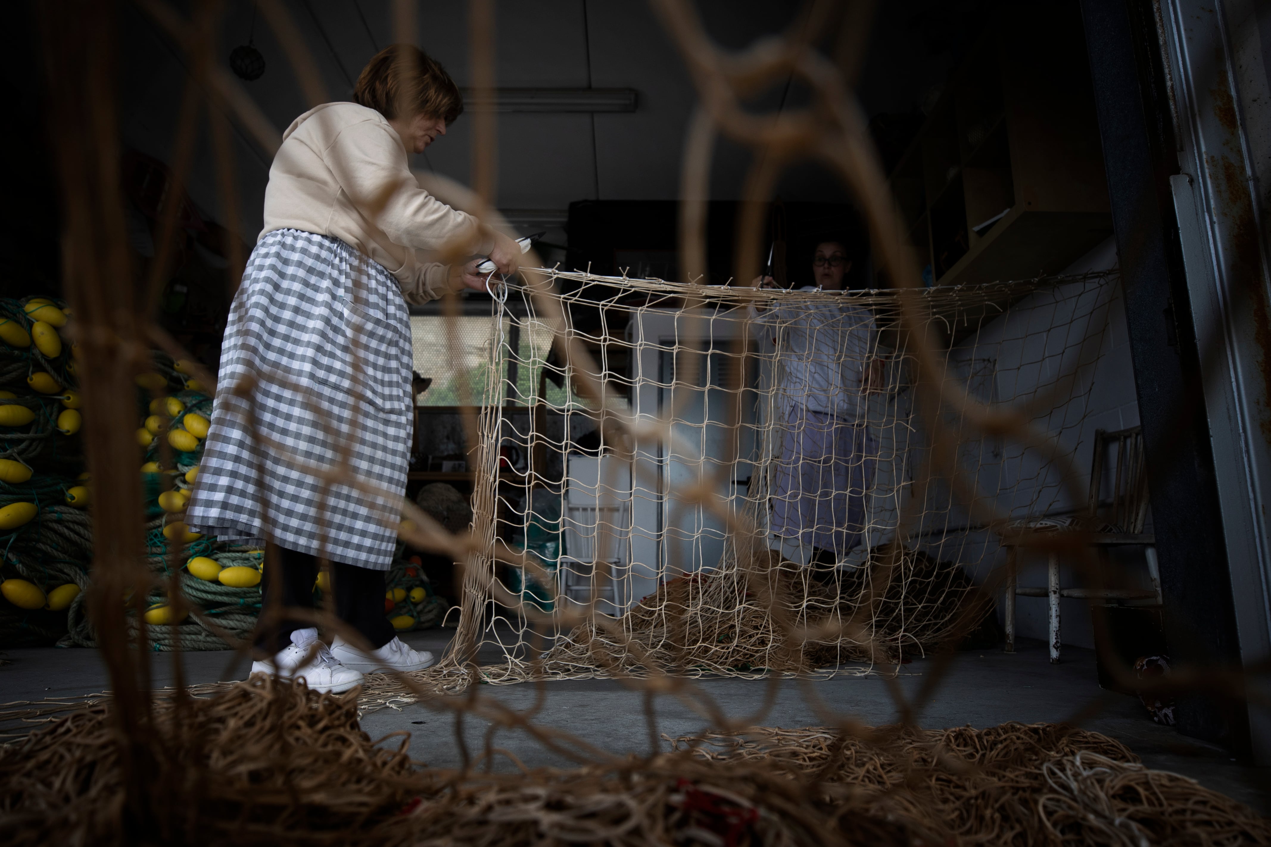 PONTECESO (A CORUÑA), 28/04/2023.- &#039;Redeiras&#039; o rederas confeccionan una red para una portería de fútbol utilizando redes recicladas en Porto de Corme, Ponteceso (A Coruña). Del mar de Galicia, al Benito Villamarín. Cien kilos de redes procedentes de residuos marinos se han transformado en las nuevas mallas del estadio bético, las que estrenó Ayoze Pérez este mes ante el Espanyol. Viajaron 900 kilómetros para tener una segunda vida. El deporte no se enreda, recicla. Los residuos marinos se convierten en material deportivo. EFE/ Cabalar
