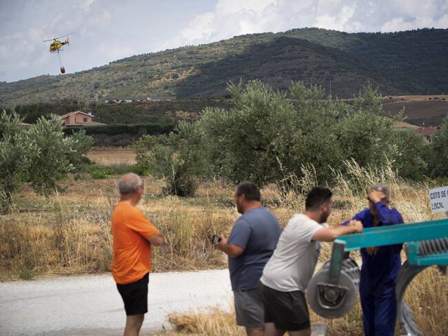 Vecinos de Eslava observan uno de los focos activos mientras un helicóptero descarga agua EFE/Villar López.