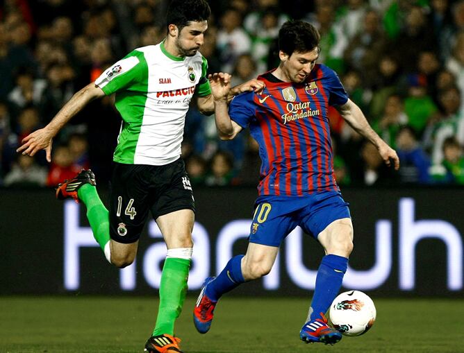 El delantero argentino del FC Barcelona Lionel Messi conduce el balón presionado por el defensa del Racing de Santander Álvaro González durante el partido, correspondiente a la vigésimo séptima jornada de Liga de Primera División, que disputan ambos equip