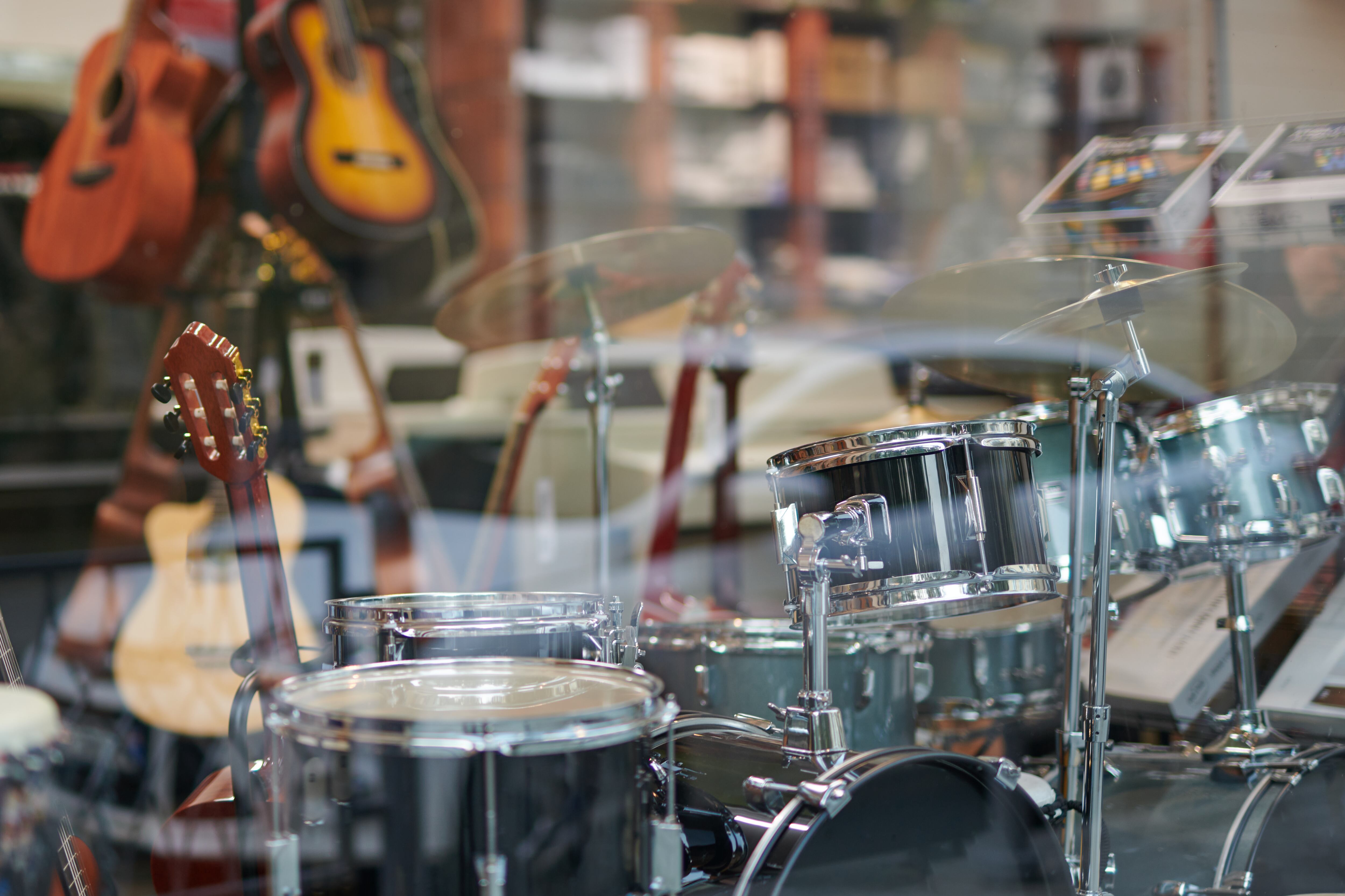 Acoustic guitars, drums and many other kinds of musical equipment displayed in the shop window of a musical instrument store. Selective focus, copy space.