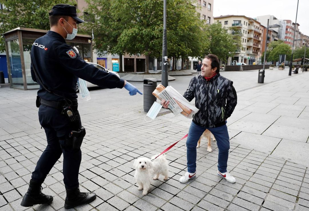 Un policía controla a un ciudadano que está paseando a su mascota.