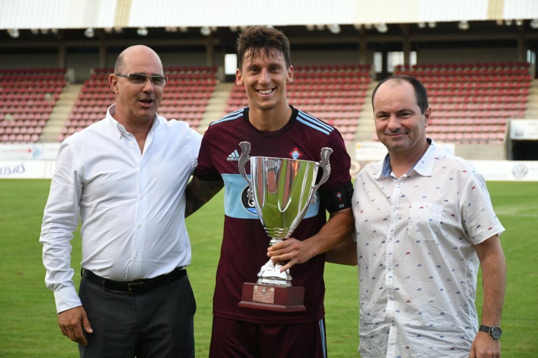 El presidente de la SD Compostela, Antonio Quinteiro (i), y el periodista de Radio Galicia Cadena SER, Antonio Bermúdez (d), entregan el trofeo de campeón del IV Memorial Antonio Bermúdez al capitán del Celta B