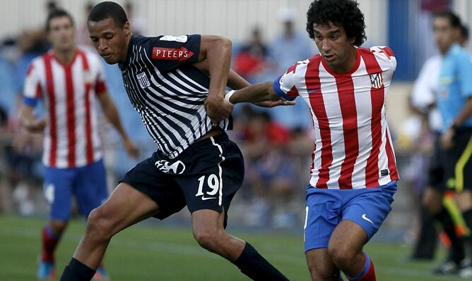 El centrocampista turco del Atlético de Madrid, Arda Turan, intenta marcharse de un jugador del Alianza de Lima, durante el partido amistoso disputado el sábado 28 de julio de 2012, en el estadio Vicente Calderón de Madrid.