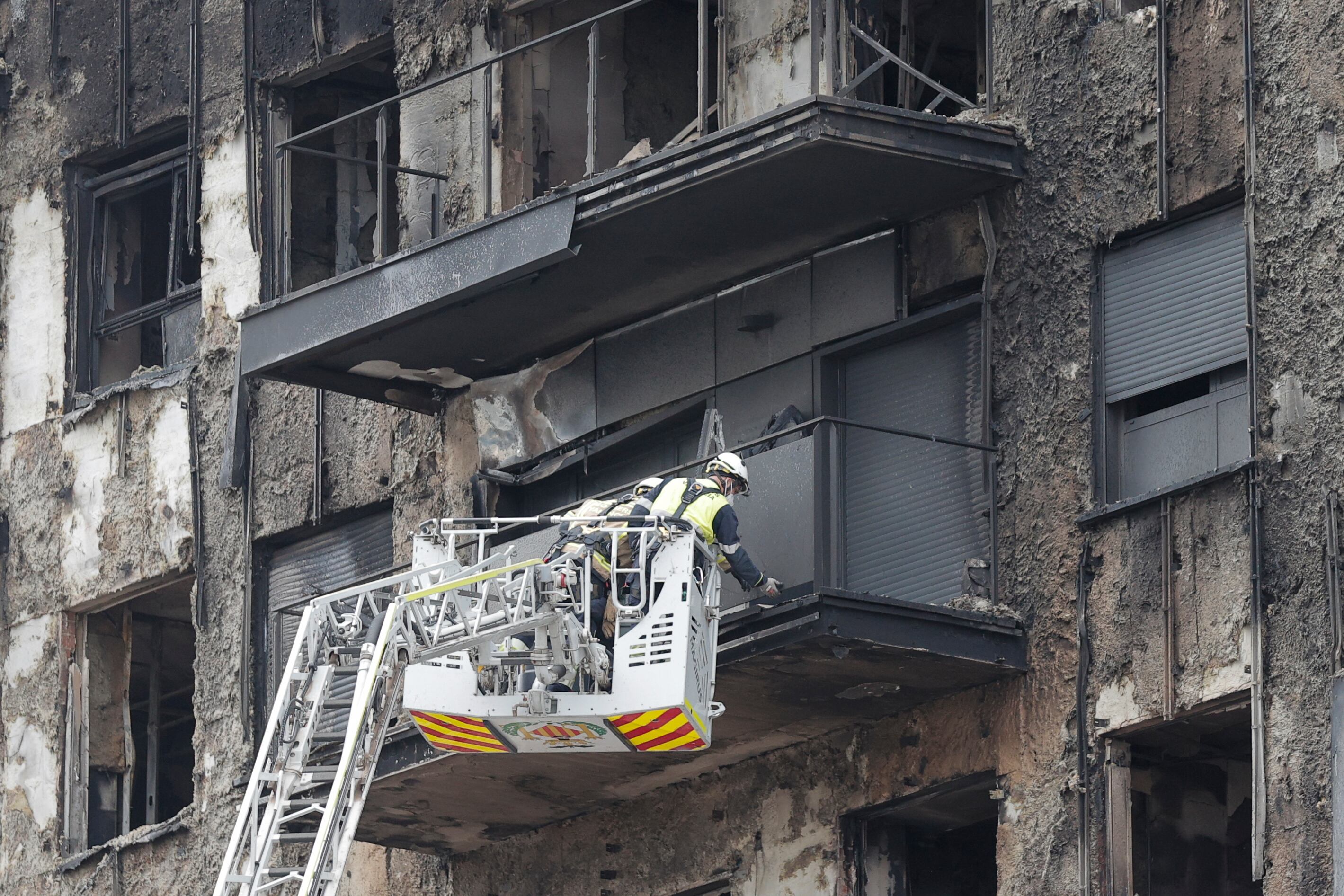Unos bomberos trabajan en el saneamiento de la fachada del edificio siniestrado en la zona del barrio valenciano de Campanar.
