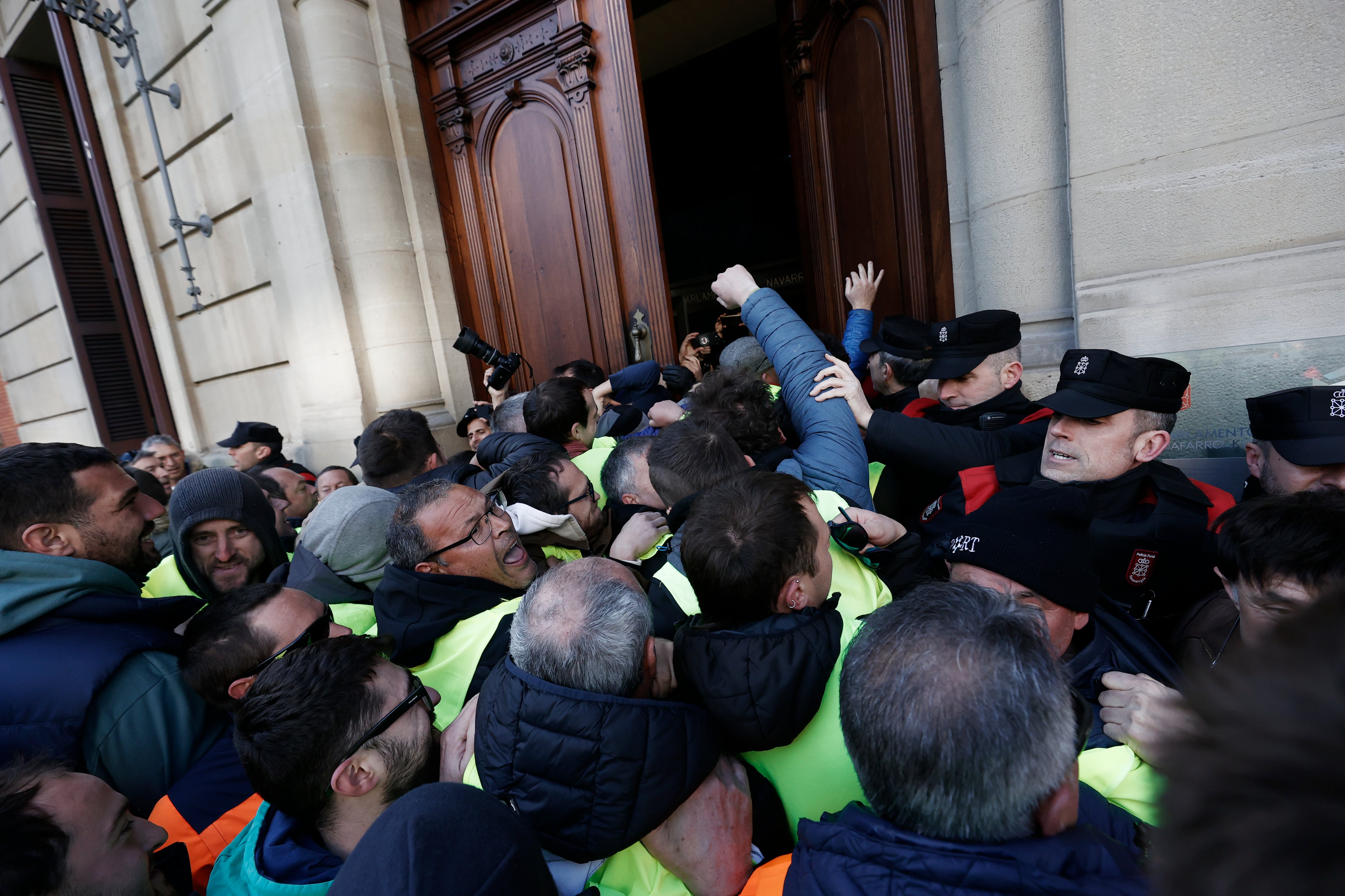 Un grupo de agricultores tratando de acceder al interior del Parlamento de Navarra