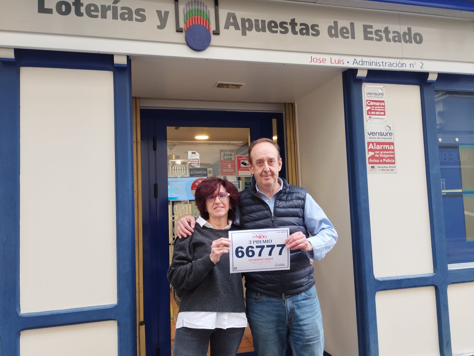 José Luis Dessy junto a su mujer Carol en la administración, mostrando el 3º premio del que vendieron unos décimos en El Niño de este año