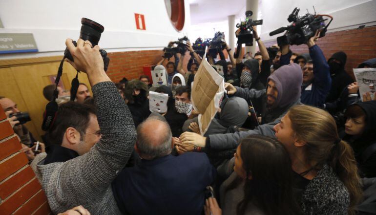 Unos 200 jóvenes, la mayoría con la cara oculta por caretas o pasamontañas, taponan desde dentro la puerta de la facultad de derecho de la Universidad Autónoma de Madrid, para impedir la entrada al expresidente del Gobierno Felipe González, que tenía prev