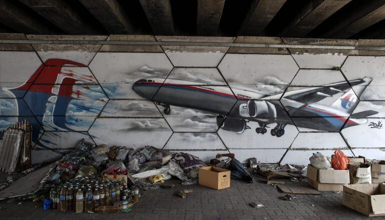 Un hombre descansa junto a un mural del vuelo desaparecido de Malaysia Airlines en Shah Alam a las afueras de Kuala Lumpur.