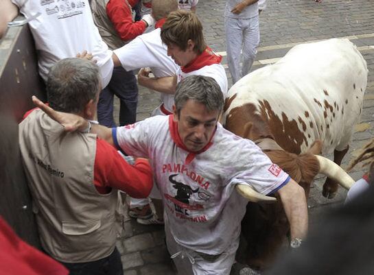 Un manso embiste a un corredor en la curva de Mercaderes durante el primero de los encierros de los sanfermines del 2011, una carrera con toros de la ganadería gaditana de Torrestrella en la que los cabestros han protagonizado las principales anécdotas