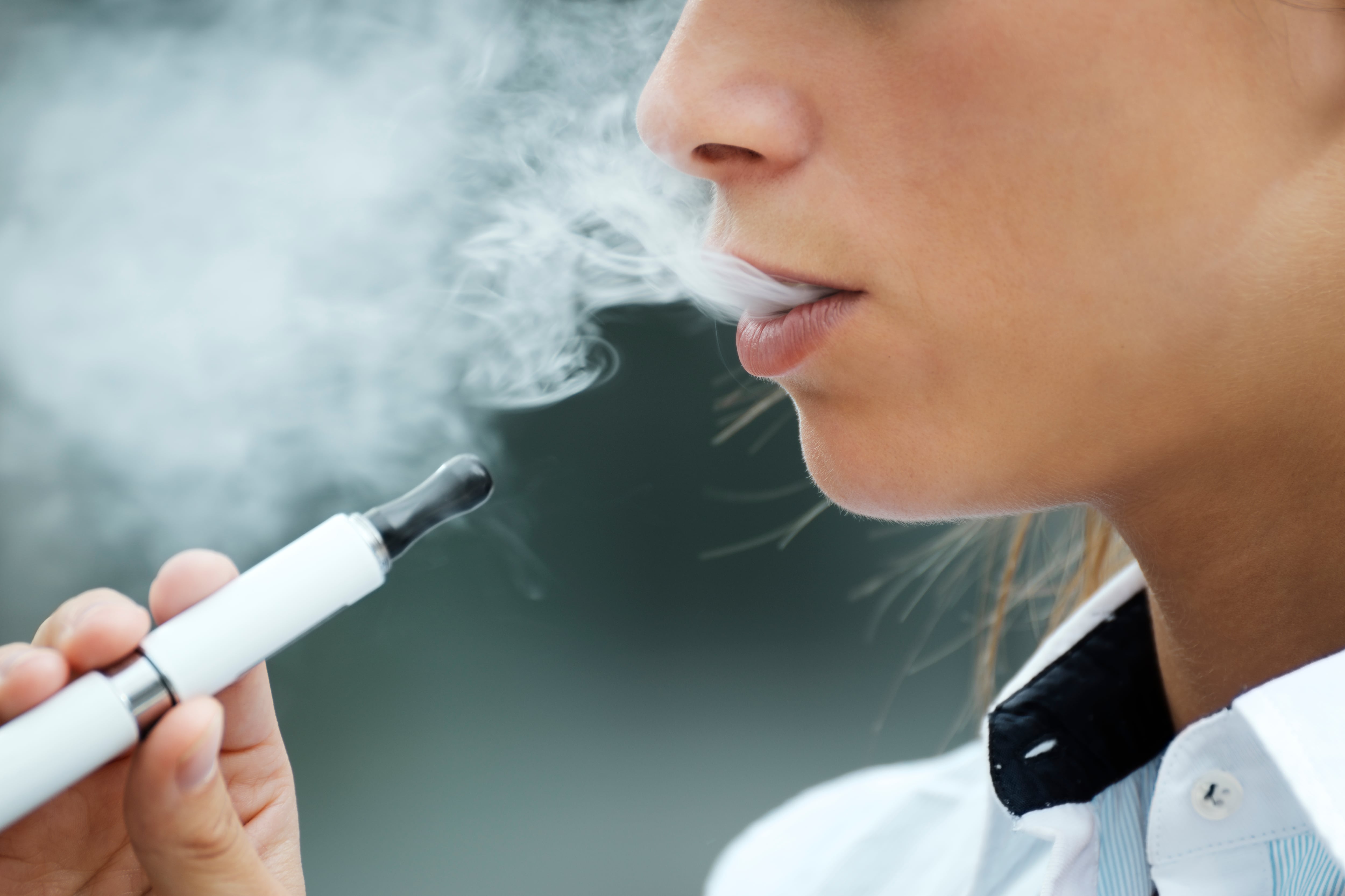 Joven inhalando humo de un cigarrillo electrónico