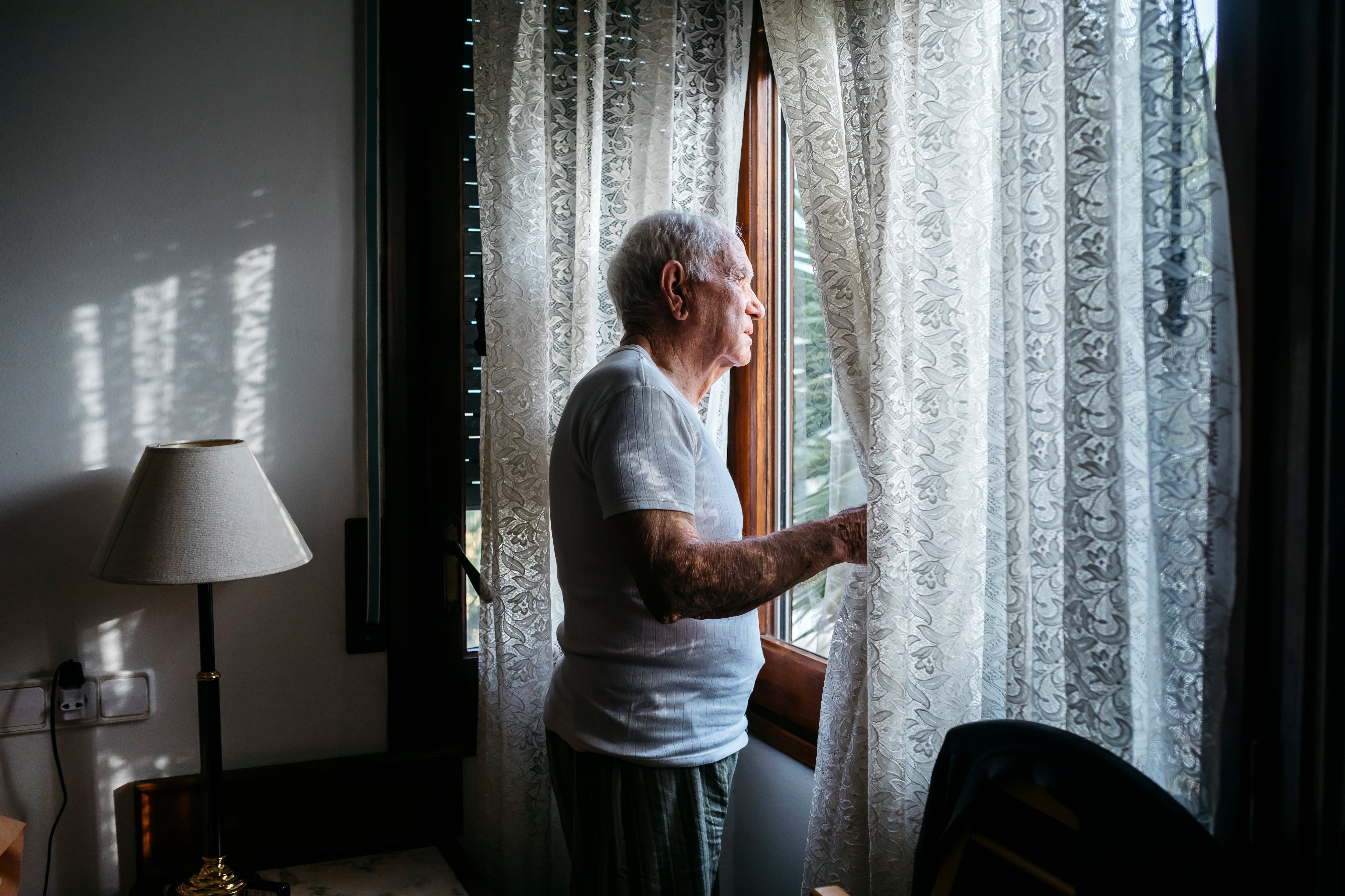 Una persona mayor se asoma por la ventana. Foto: Getty Images