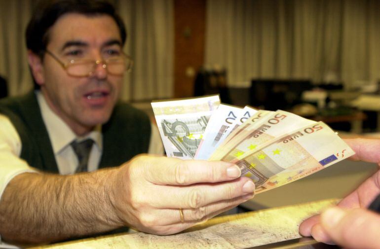 Un empleado de banca muestra billetes de euro.