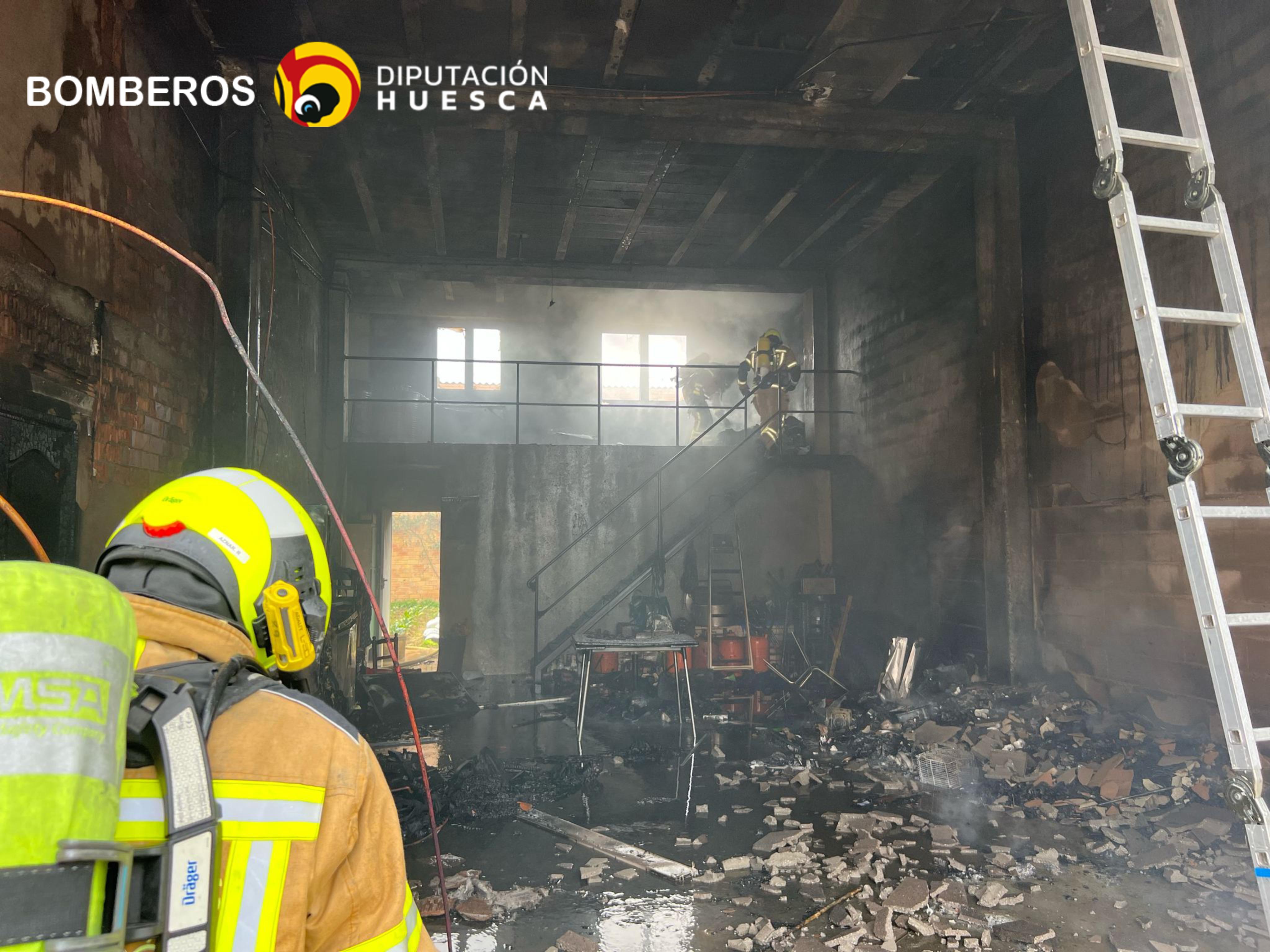 Los bomberos actuando en el incendio en el interior del almacén